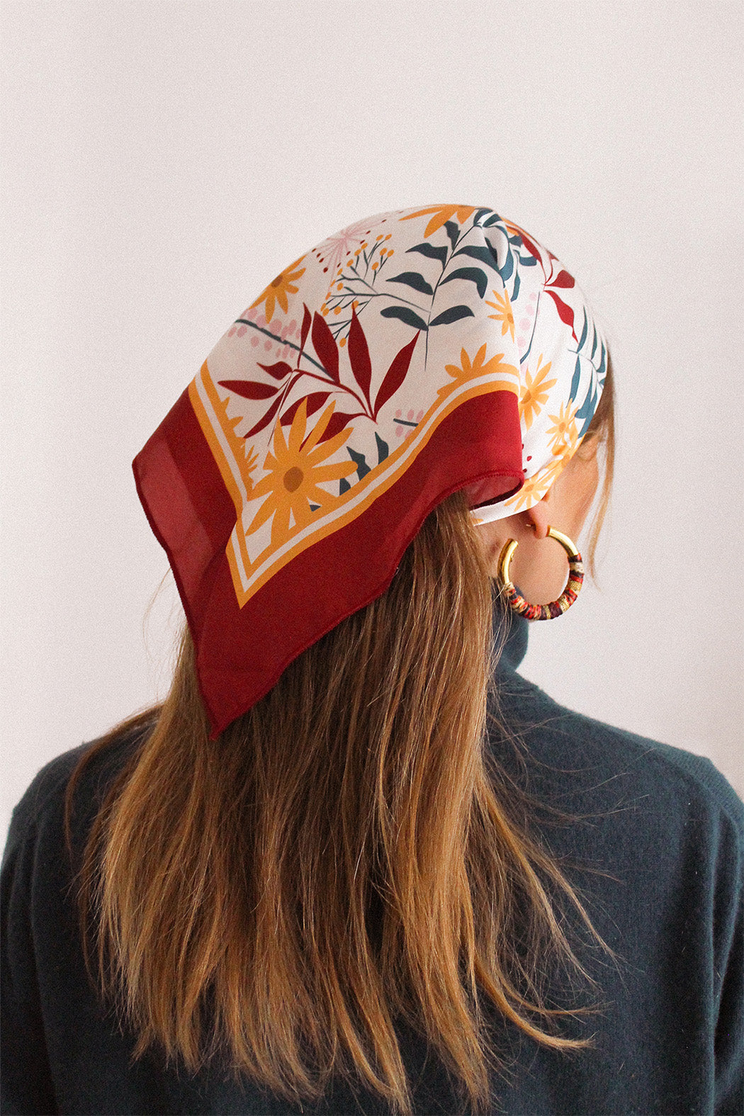 Femme portant un foulard coloré, rouge, blanc, jaune et vert, sur la tête pour attacher ses cheveux