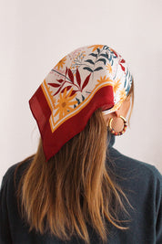 Femme portant un foulard coloré, rouge, blanc, jaune et vert, sur la tête pour attacher ses cheveux