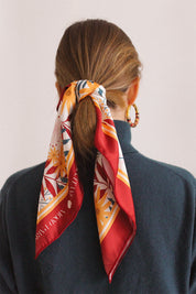 Femme portant un foulard tendance pour l'été de couleur rouge, blanc, jaune, vert et orange pour attacher les cheveux